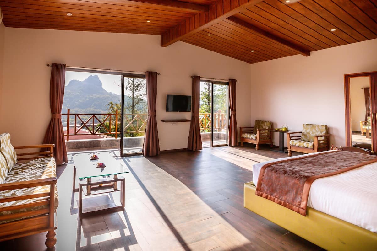 Una habitación de hotel con cama, sofá, mesa y televisor.