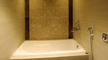 A modern bathroom with a wooden ceiling, a large bathtub, and a toilet.