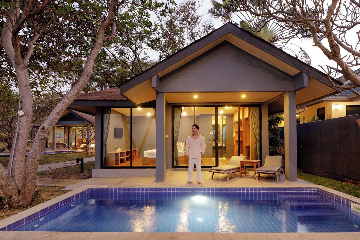 A modern house with a swimming pool, large glass doors, and a covered patio area.