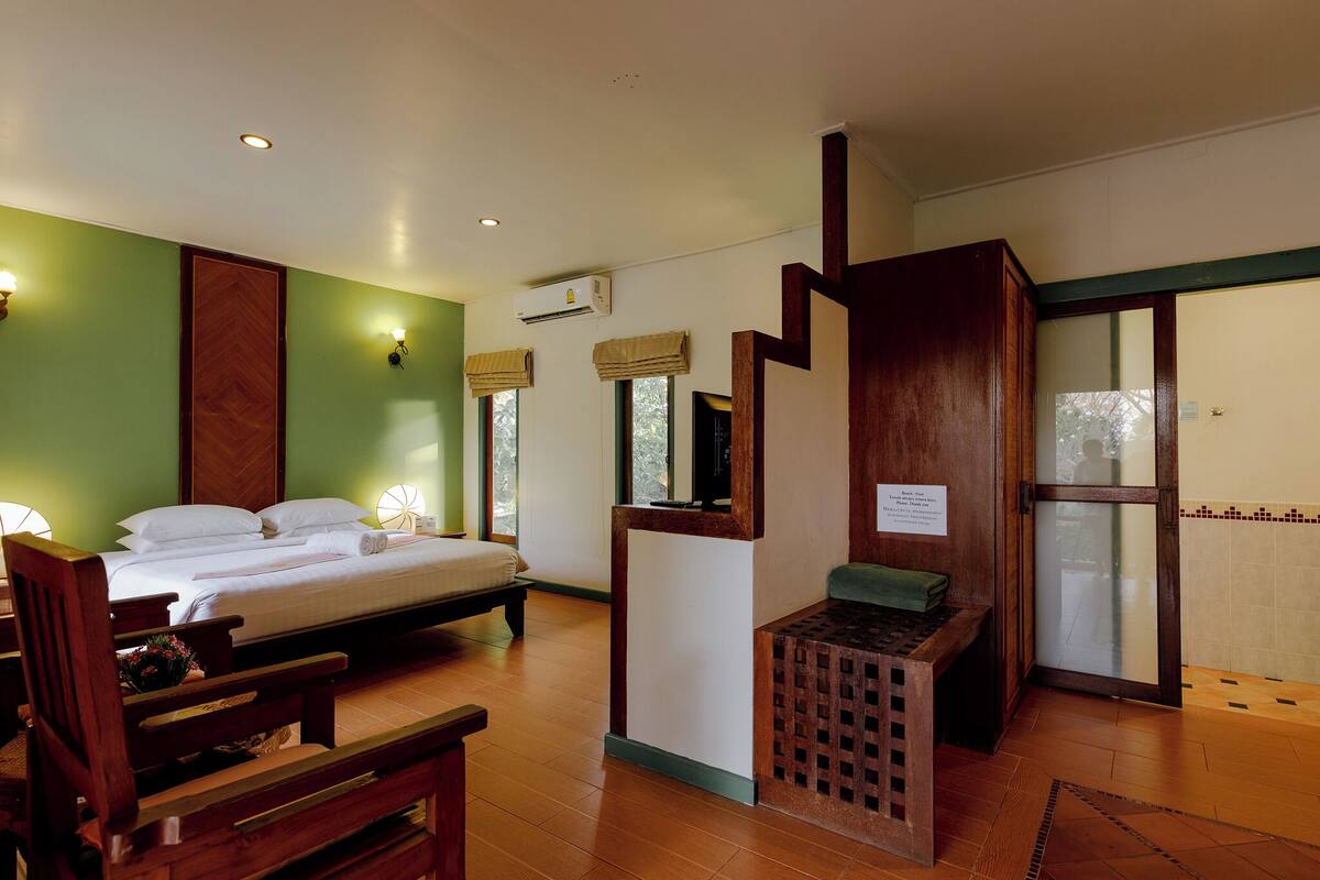A hotel room with a bed, wooden furniture, a small table, and a window with a view.