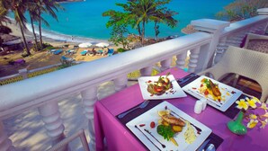 A balcony with a table set for a meal, overlooking a beach with palm trees and the ocean. - The Bay Samui (Koh Samui)