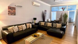 A modern living room with a sectional sofa, a coffee table, and a dining area with a table and chairs. - Luxurious, spacious and modern apartment in a superb central location.  (Barcelona)