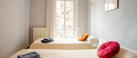 Una habitación de hotel con dos camas, una ventana con vistas, un radiador y un espejo en la pared.
