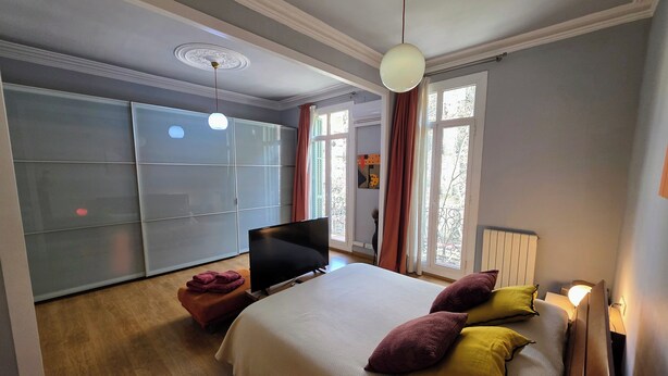 A bedroom with a bed, TV, and a large window with curtains. - Luxurious, spacious and modern apartment in a superb central location.  (Barcelona)