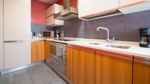 A modern kitchen with stainless steel appliances, wooden cabinets, and a double sink. - Luxurious, spacious and modern apartment in a superb central location.  (Barcelona)