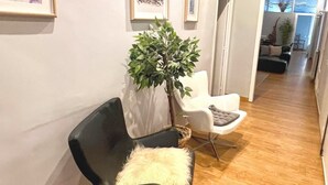 A modern hallway with a black leather chair, a white chair, and a potted plant. - Luxurious, spacious and modern apartment in a superb central location.  (Barcelona)