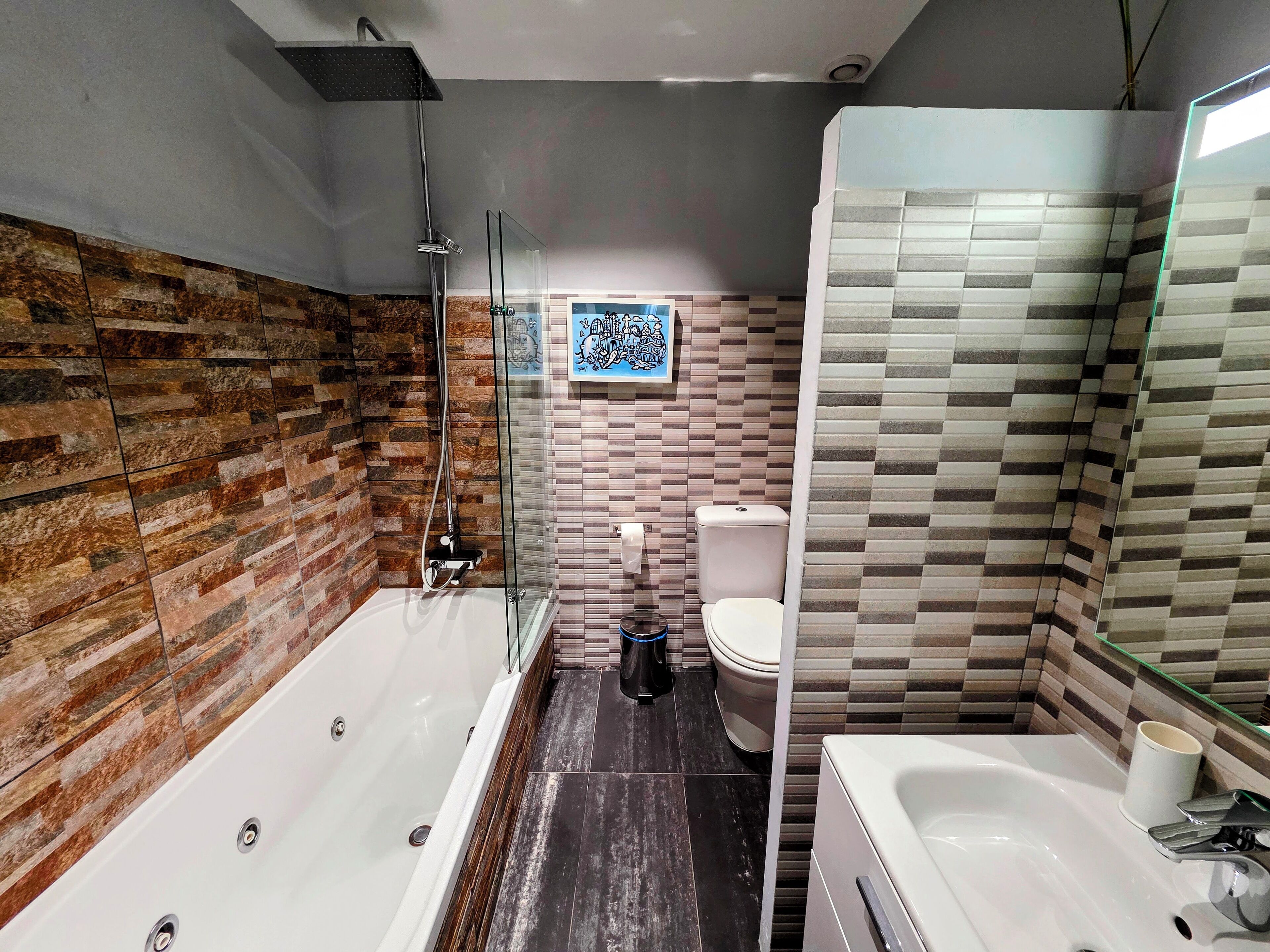 Een moderne badkamer met een douchecabine, een badkuip, een toilet en een wastafel.