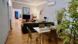 A modern living room with a dining area, wooden flooring, a flat-screen TV, a sofa, and a dining table with chairs. - Luxurious, spacious and modern apartment in a superb central location.  (Barcelona)