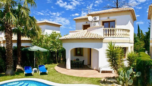 Une maison à deux étages avec une piscine, un patio doté de chaises et un petit jardin planté de cactus.