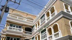 Un edificio de varios pisos con balcones, un letrero que dice "TAKIAB VINTAGE" y un cartel de "ROOM FOR RENT".