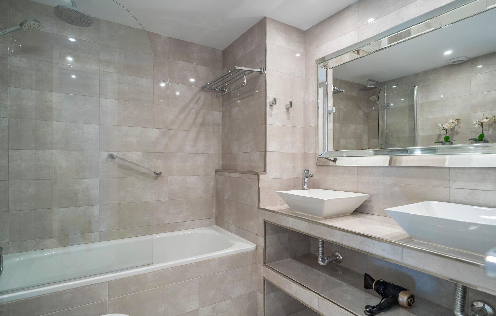 A modern bathroom with a bathtub, a shower, and a large mirror above a sink.