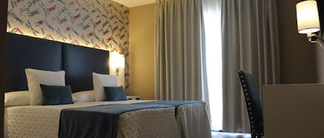 A hotel room with a large bed, a desk, and a chair.