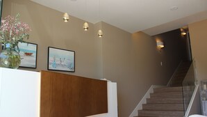 A reception desk with a wooden panel, a vase with flowers, and two framed pictures on the wall. - Hotel Aquaria Caneliñas (Sanxenxo)