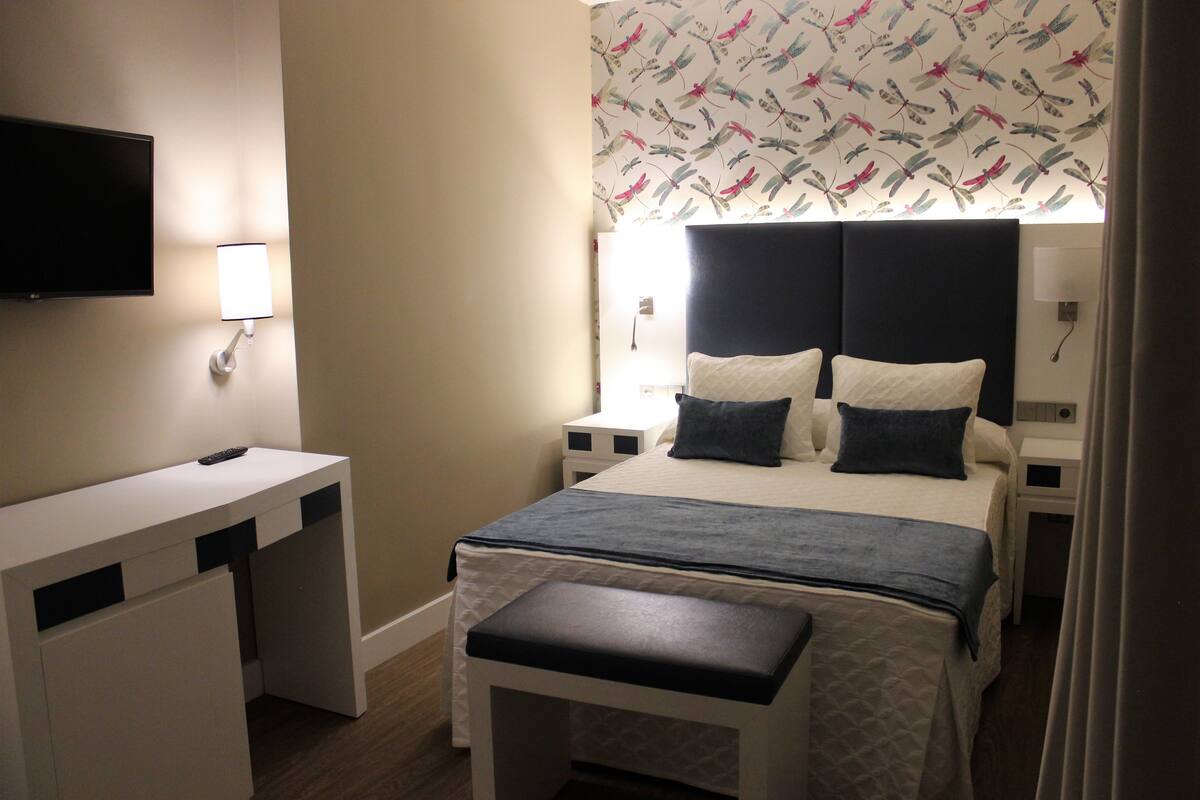 Ein Hotelzimmer mit Bett, Nachttischen, Fernseher und Schreibtisch.