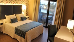 A hotel room with a large bed, a desk with a chair, a window with curtains, and a view of the outdoors. - Hotel Aquaria Caneliñas (Sanxenxo)