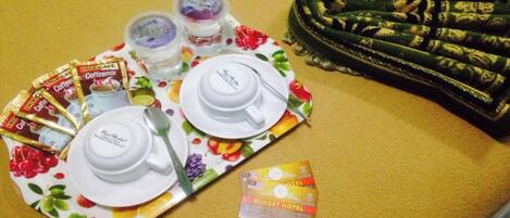 Una bandeja con sobres de café, un juego de té y un folleto del hotel sobre una superficie amarilla.