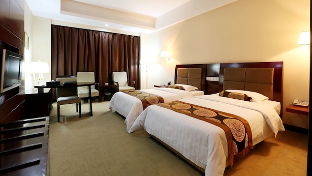 Habitación de hotel con dos camas, un escritorio, una silla, un televisor y un teléfono.