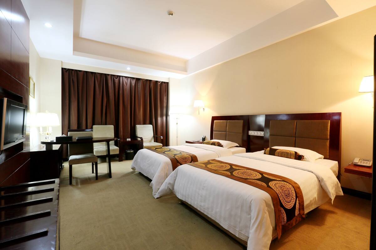Une chambre d’hôtel avec deux lits, un bureau, une chaise, une télévision et un téléphone.