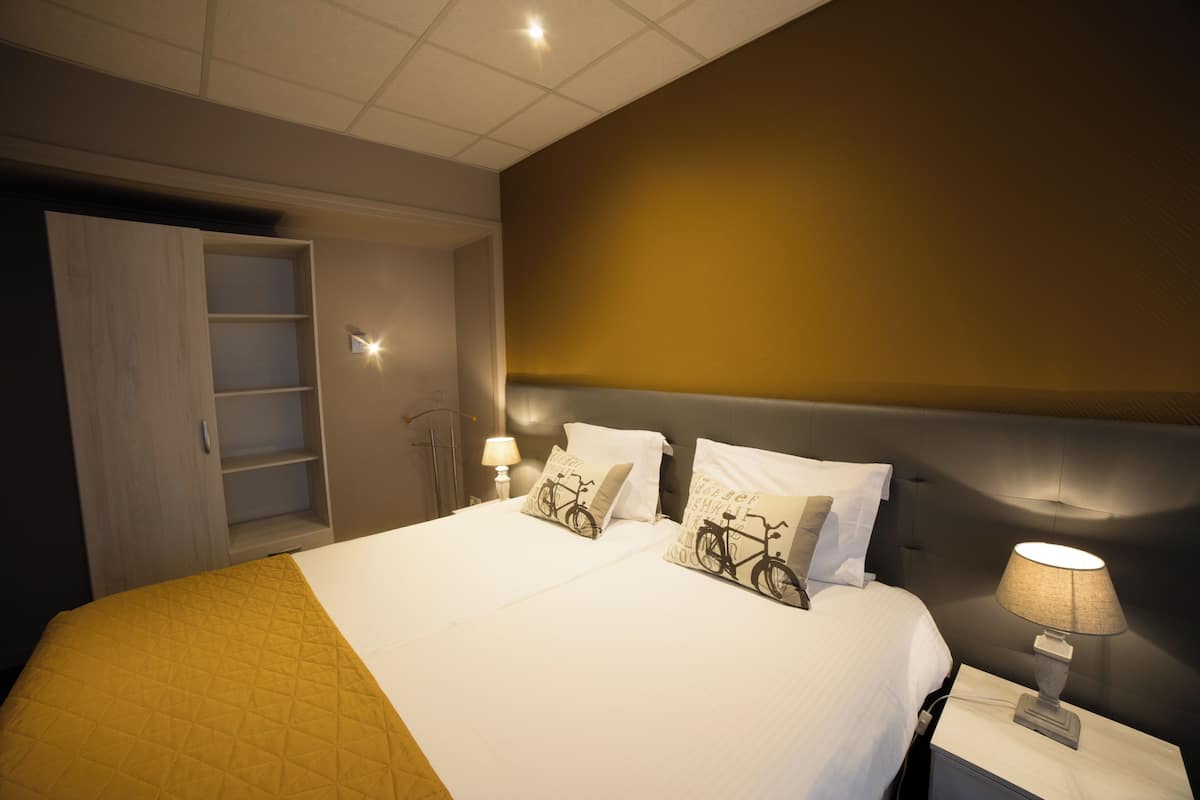 Ein Hotelzimmer mit einem großen Bett, zwei Nachttischlampen, einem Kleiderschrank und einem Nachttisch.