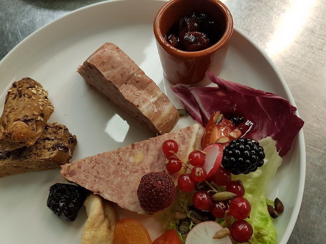 Un plato con diferentes alimentos, como pan, carne, y una mezcla de frutas y frutos secos.