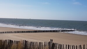 A beach with a wooden fence, ocean view, and a clear sky. - Hotel Restaurant De Eenhoorn (Oostburg)