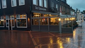 A brick building with the sign "De Eenhoorn" and a glass storefront. - Hotel Restaurant De Eenhoorn (Oostburg)