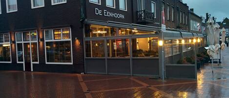 A brick building with the sign "De Eenhoorn" and a glass storefront.
