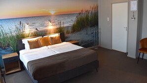 A bedroom with a bed, nightstand, and a view of the ocean at sunset. - Hotel Restaurant De Eenhoorn (Oostburg)