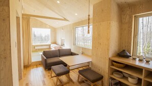 Een houten interieur met een bank, een zitbank, een tafel en planken.