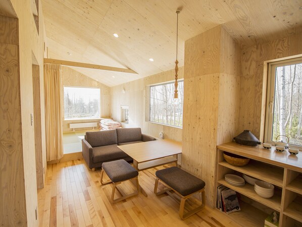 Un interior de madera con sofá, banca, mesa y estanterías.