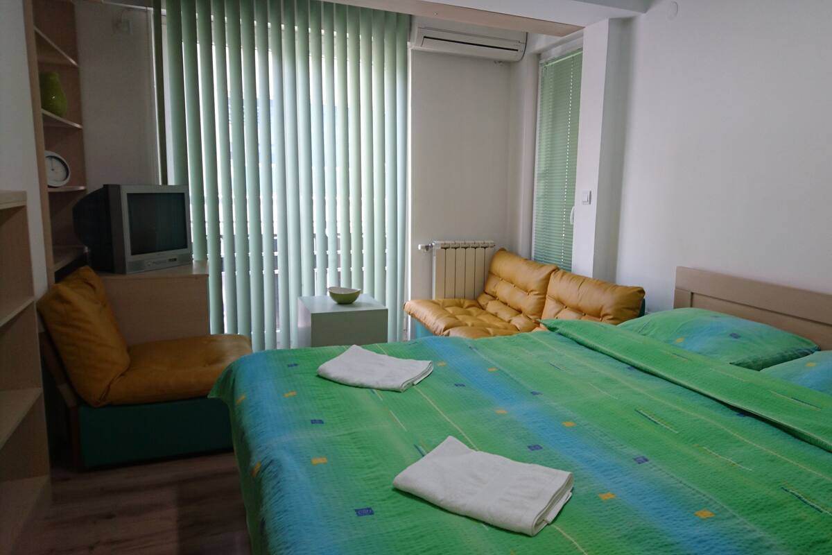 Et hotelværelse med en seng, en stol, et lille bord med en skål og et fjernsyn på en hylde.