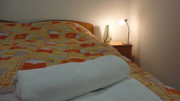 Cama bem arrumada com colcha estampada e duas toalhas brancas dobradas.