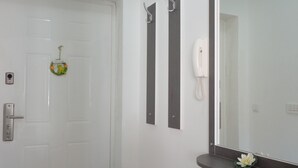 Una puerta blanca con un letrero de bienvenida, un teléfono y un espejo con una flor en la pared.