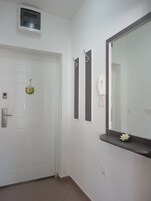 Una puerta blanca con un letrero de bienvenida, un teléfono y un espejo con una flor en la pared.
