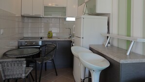 Una cocina compacta con comedor, que incluye una mesa pequeña, sillas, un lavamanos y un refrigerador.