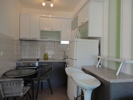 Una cocina compacta con comedor, que incluye una mesa pequeña, sillas, un lavamanos y un refrigerador.