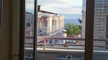 Un balcón con vista a un edificio en construcción, una antena parabólica y una masa de agua al fondo.