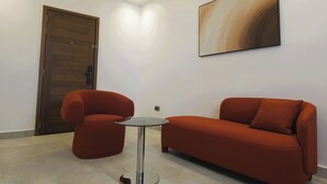 Ein modernes Zimmer mit Holztür, einem roten Sofa, einem kleinen runden Tisch und einer Wand-Klimaanlage.