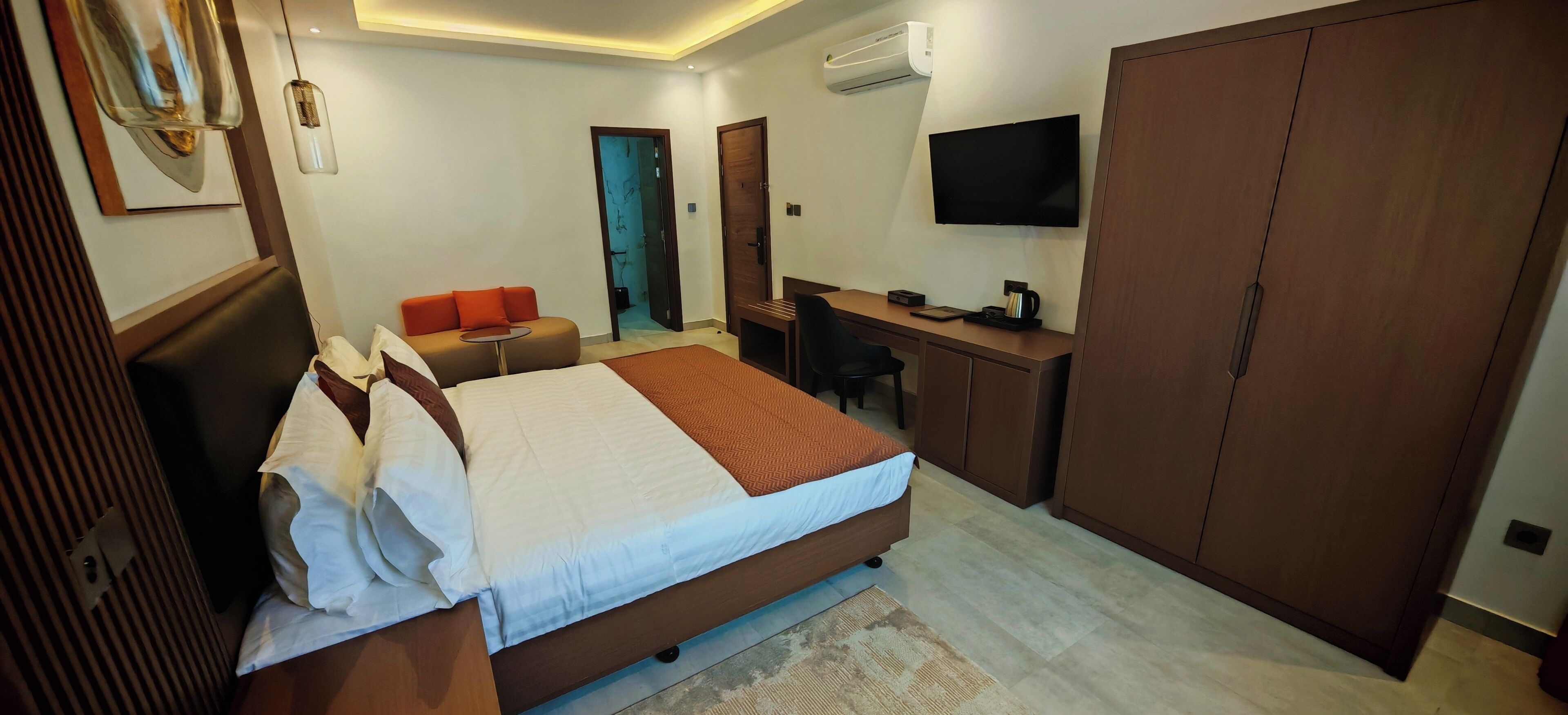 Une chambre d’hôtel avec un lit, un bureau, une télévision et une armoire.