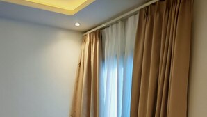 Ein modernes Wohnzimmer mit einem roten Sofa, einem kleinen runden Tisch und beigen Vorhängen.