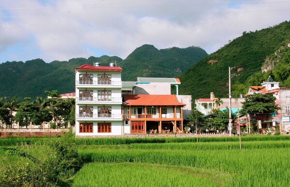 Situated in a serene rural setting, this traditional building offers a peaceful retreat amidst lush green surroundings and majestic mountains.