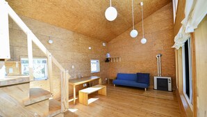 A wooden interior with a sofa, a TV, a bench, and a table. - Moon Cabin (Kutchan)