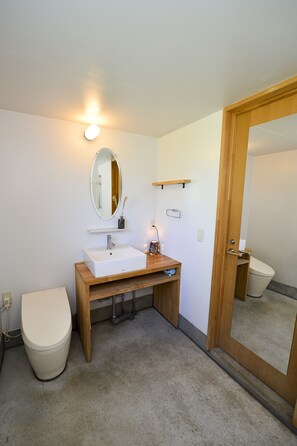 Un baño con lavamanos, espejo y retrete blancos.