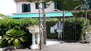 A gated entrance with a sign indicating an entrance to a restaurant. - Auberge Les Arômes (Grasse)