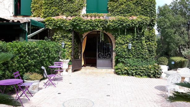 A courtyard with a brick pathway, purple chairs, and a white table. - Auberge Les Arômes (Grasse)