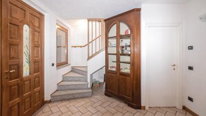 Un couloir avec une porte en bois, une porte en verre et un escalier menant à une autre pièce.