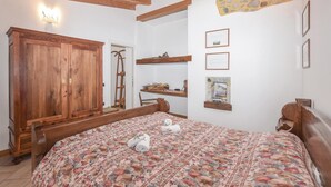 Une chambre avec un lit en bois, une armoire, une échelle et des tableaux encadrés accrochés au mur.