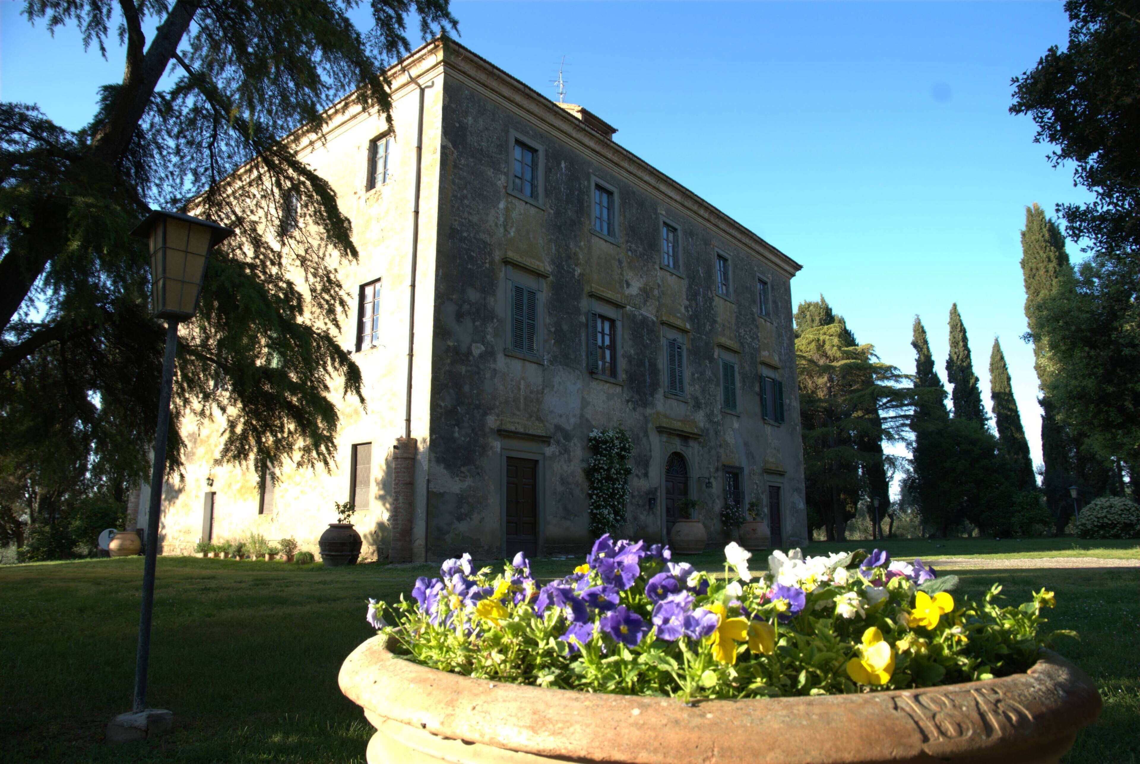 Um edifício histórico com um grande jardim na frente.