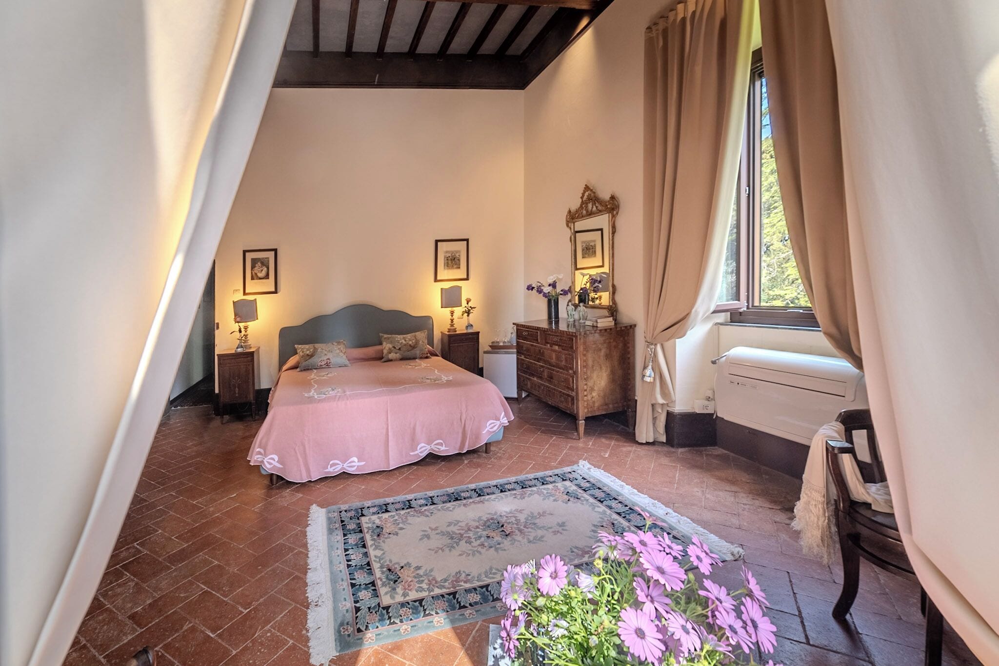 A bedroom with a bed, bedside tables, a dresser, a mirror, and a window with curtains.