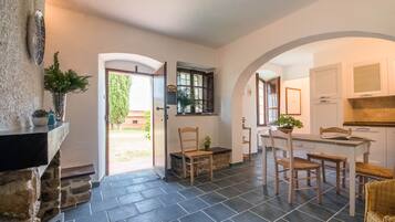A kitchen with a dining area, stone walls, and a view of the outdoors.